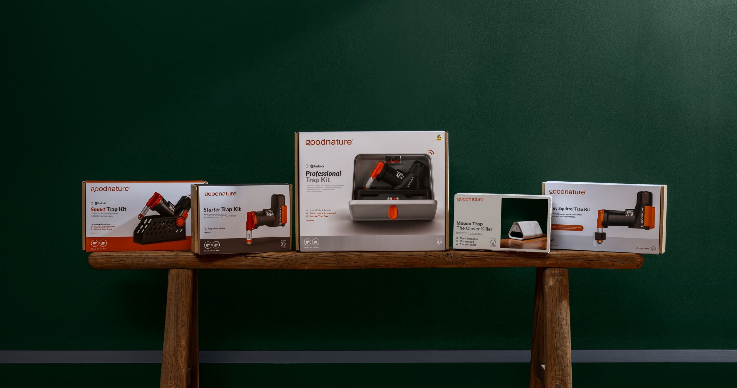 Five rectangular boxes with images and descriptions of electronic devices arranged on a wooden bench against a dark green wall background